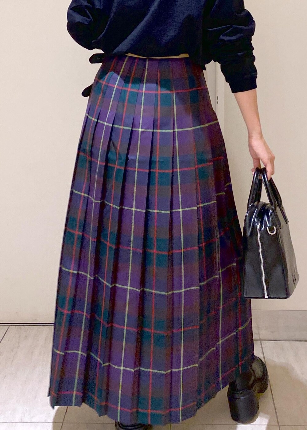 ブラック系のボストンバッグ、ブラック系のブーツ、パープル系のスカートを着用したレディースの秋コーディネートの8枚目の写真