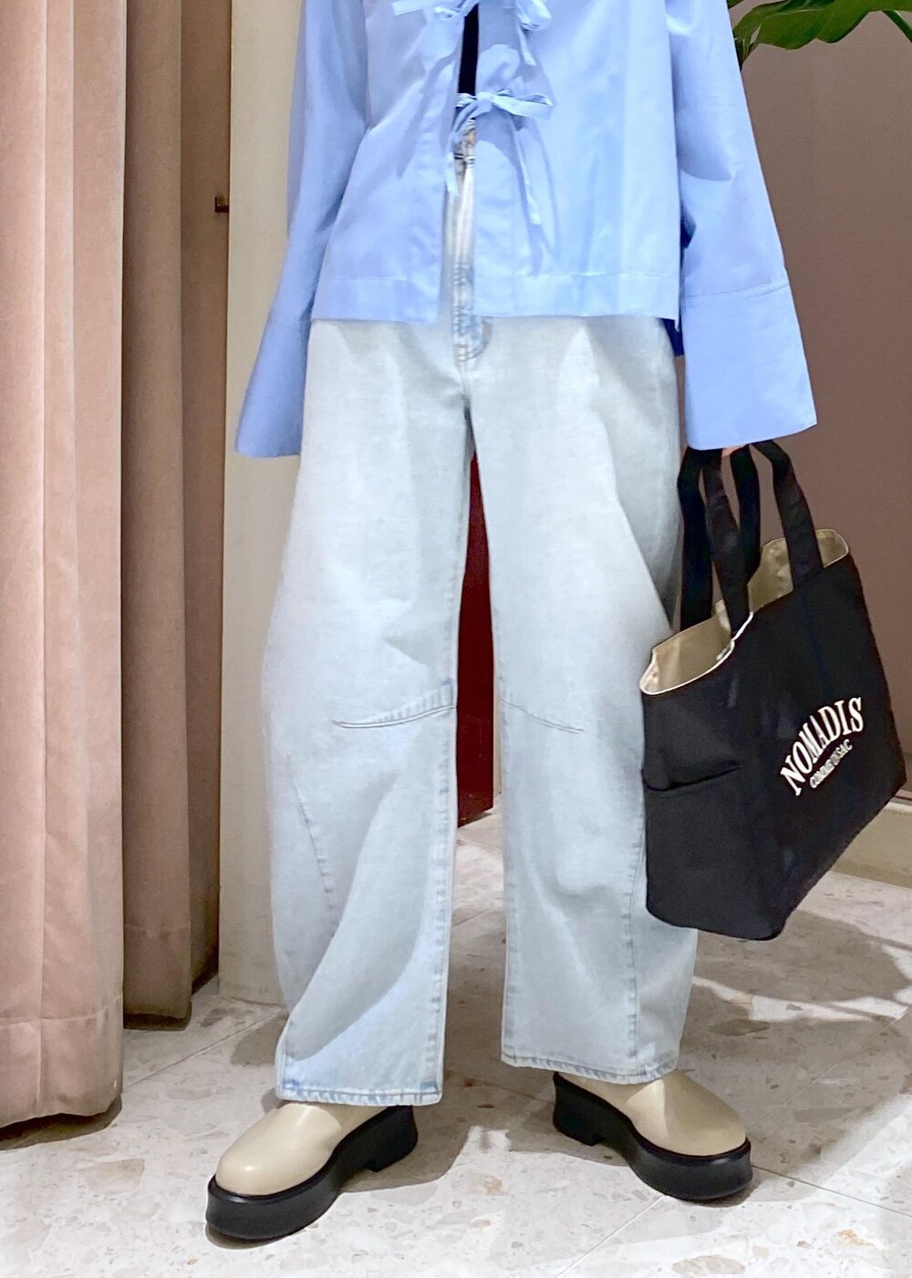 ブルー系のデニムパンツ、ブラック系のトートバッグ、ベージュ系のサンダルを着用したレディースの秋コーディネートの9枚目の写真