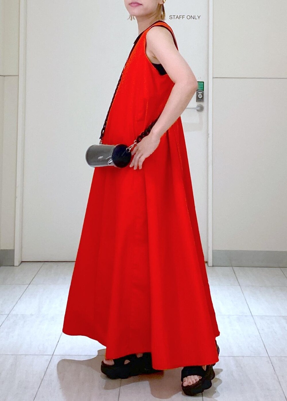 ブラック系のサンダル、ブラック系のドラムバッグ、レッド系のワンピースを着用したレディースの夏コーディネートの7枚目の写真