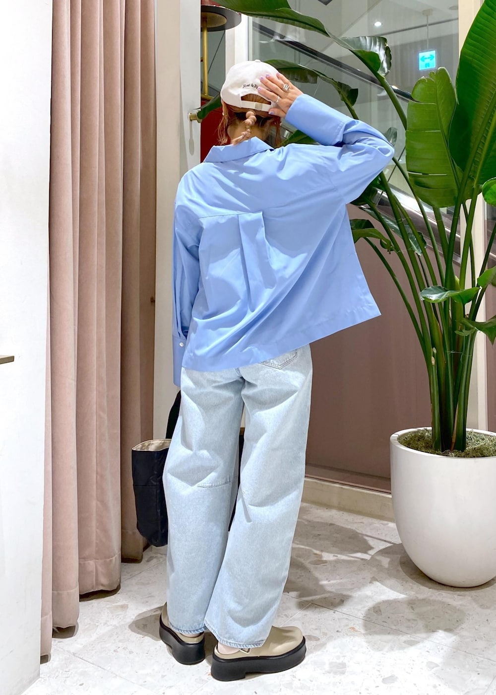 ブルー系のデニムパンツ、ブラック系のトートバッグ、ベージュ系のサンダルを着用したレディースの秋コーディネートの4枚目の写真