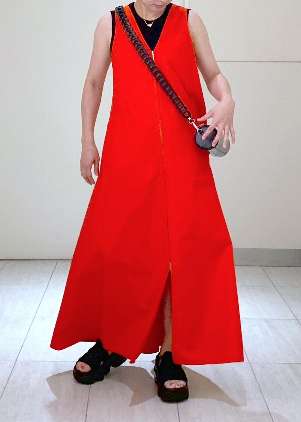 ブラック系のサンダル、ブラック系のドラムバッグ、レッド系のワンピースを着用したレディースの夏コーディネートの4枚目の写真