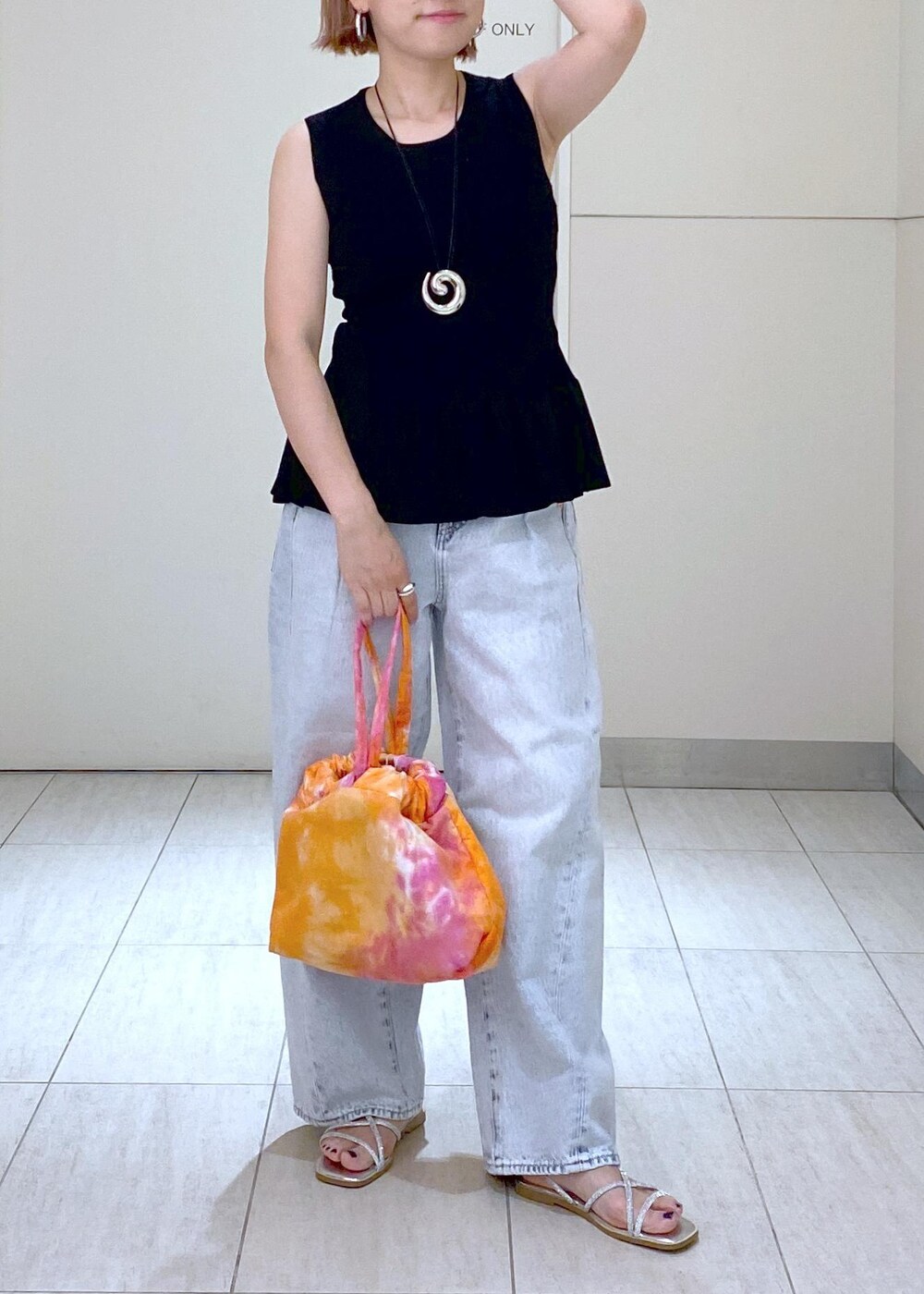 シルバー系のサンダル、ブラック系のニット/セーター、ブルー系のデニムパンツを着用したレディースの春コーディネートの2枚目の写真