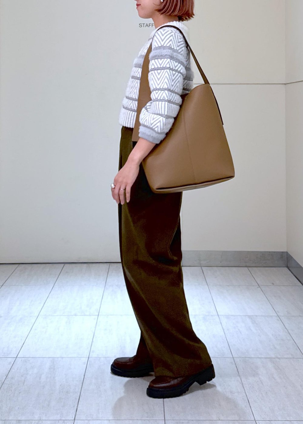 ホワイト系のカーディガン/ボレロ、グリーン系のスラックス、ブラウン系のハンドバッグを着用したレディースの秋コーディネートの9枚目の写真