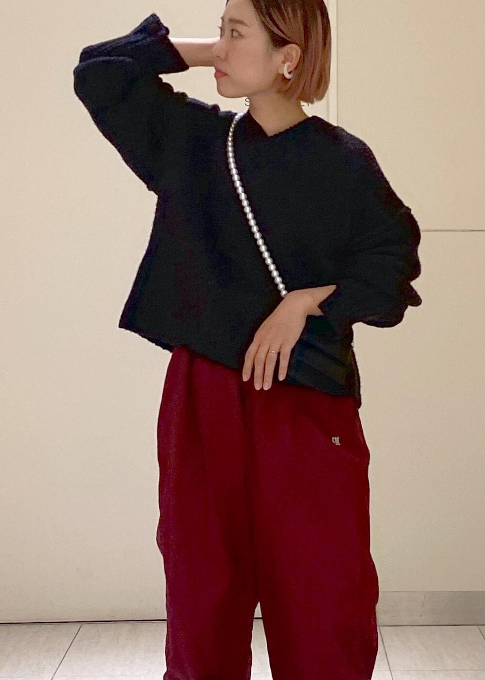 ブラック系のニット/セーター、ブラック系のショルダーバッグ、レッド系のその他パンツを着用したレディースの秋コーディネートの4枚目の写真