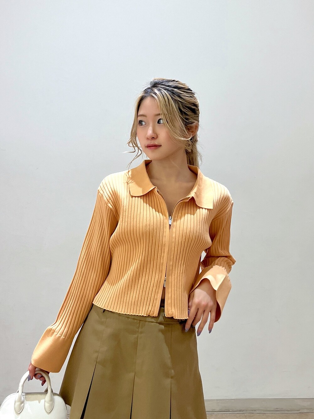 ベージュ系のニット/セーター、ホワイト系のショルダーバッグ、ベージュ系のスカートを着用したレディースの冬コーディネートの6枚目の写真