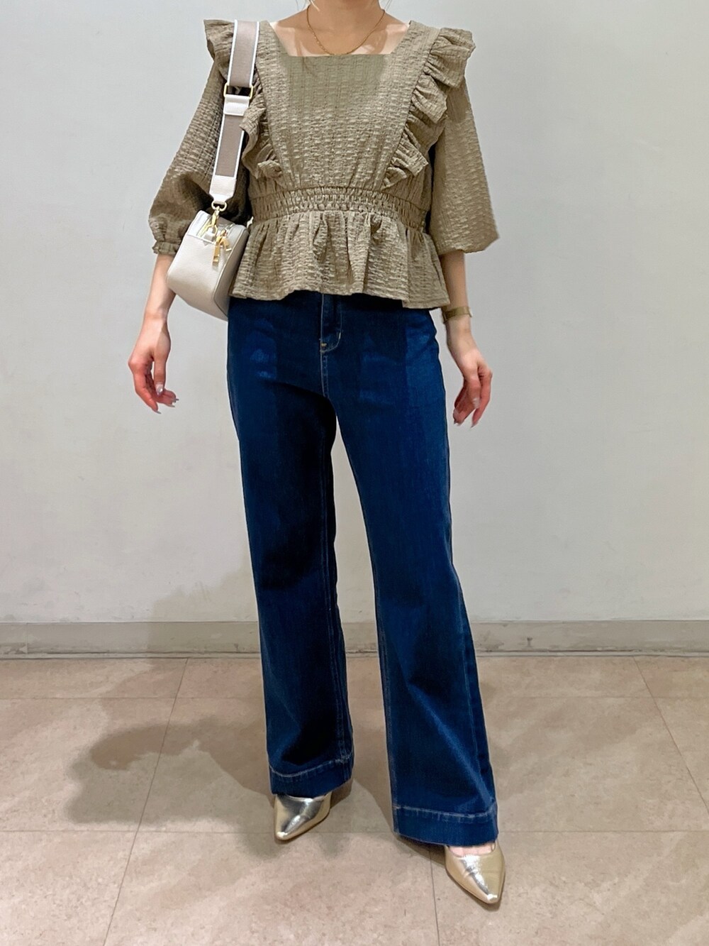 ブラウン系のシャツ/ブラウス、ブルー系のデニムパンツ、ゴールド系のパンプスを着用したレディースの春コーディネートの2枚目の写真