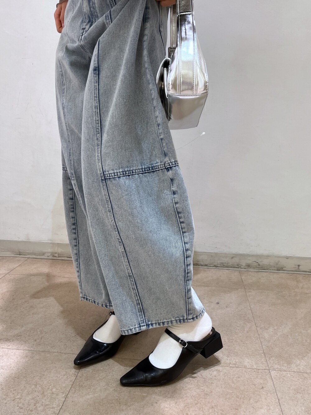 ブラック系のシャツ/ブラウス、シルバー系のショルダーバッグ、ブルー系のデニムパンツを着用したレディースの春コーディネートの10枚目の写真