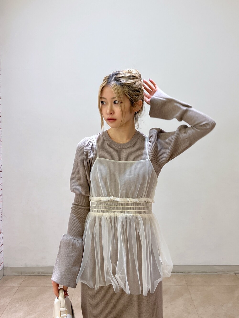 ホワイト系のショルダーバッグ、ブラック系のブーツ、ベージュ系のワンピースを着用したレディースの冬コーディネートの5枚目の写真