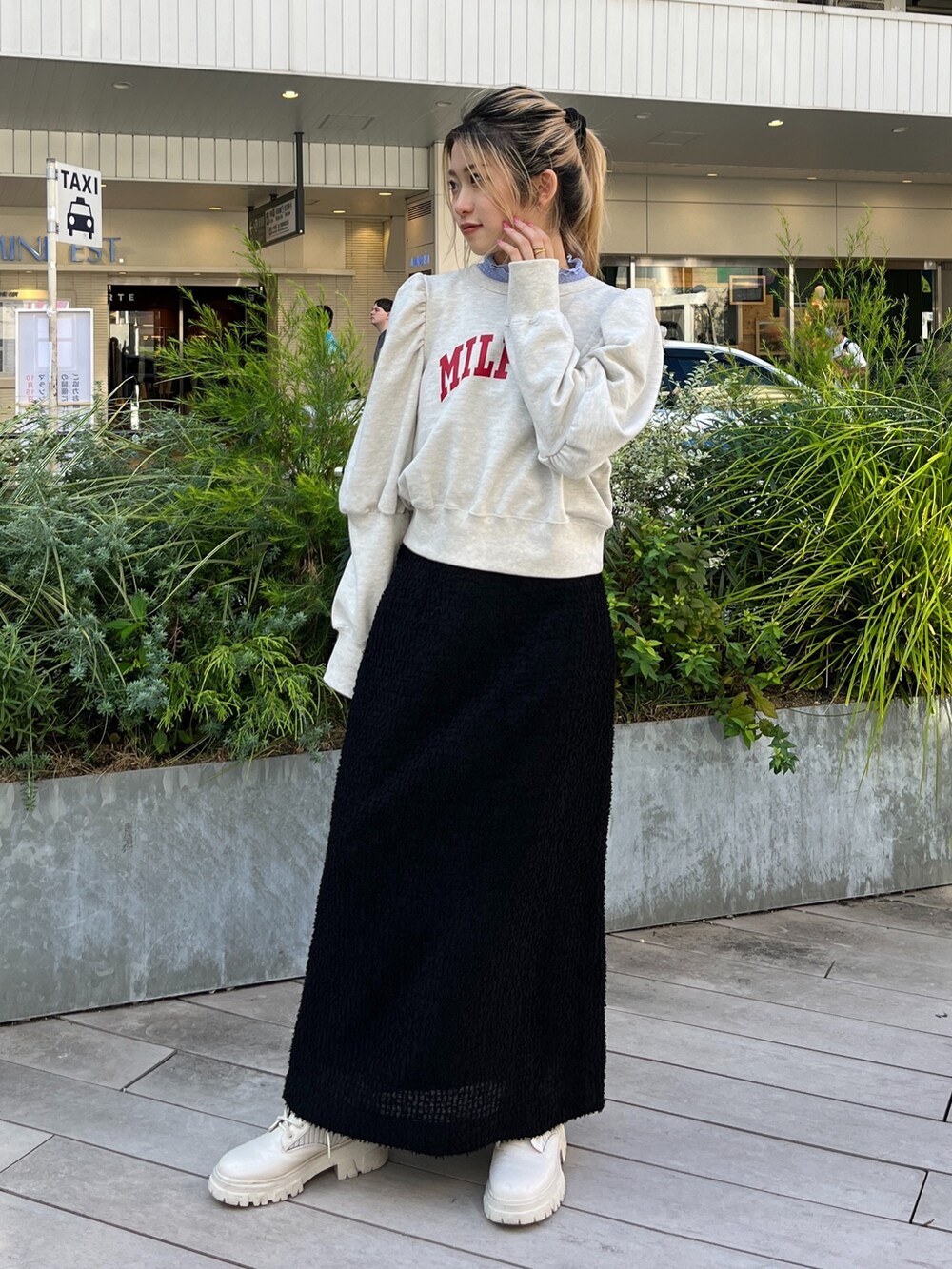 ホワイト系のスウェット、ホワイト系のブーツ、ブラック系のスカートを着用したレディースの秋コーディネートの2枚目の写真