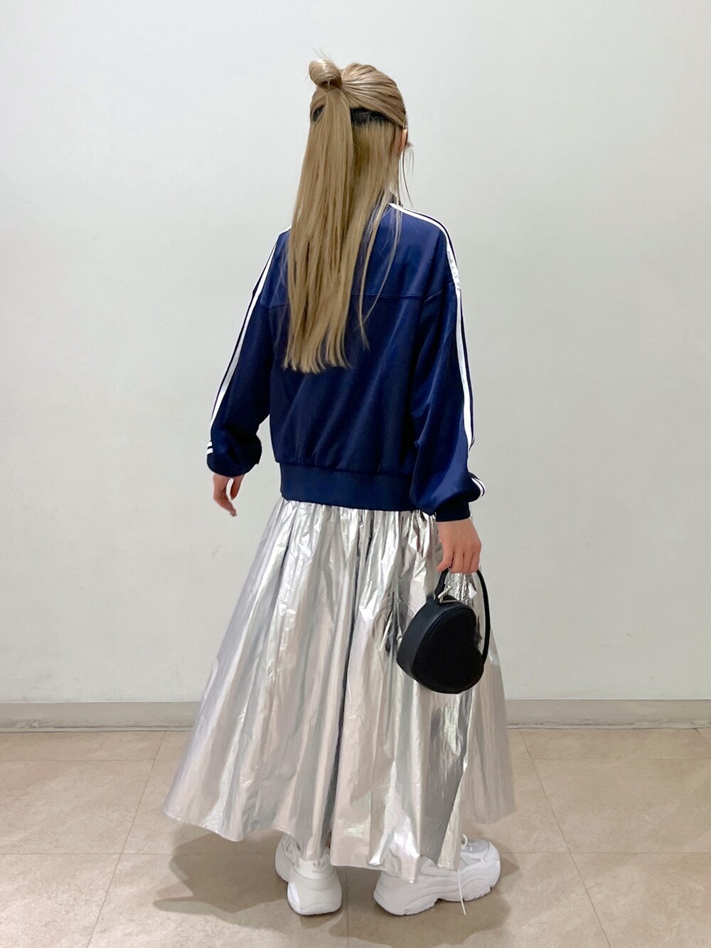 ブルー系のブルゾン、ブラック系のショルダーバッグ、シルバー系のスカートを着用したレディースの春コーディネートの3枚目の写真