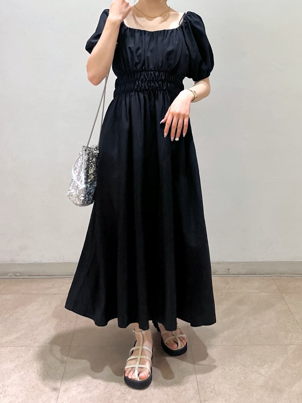 ブラック系のワンピース、シルバー系のハンドバッグ、ホワイト系のサンダルを着用したレディースの春コーディネートの8枚目の写真