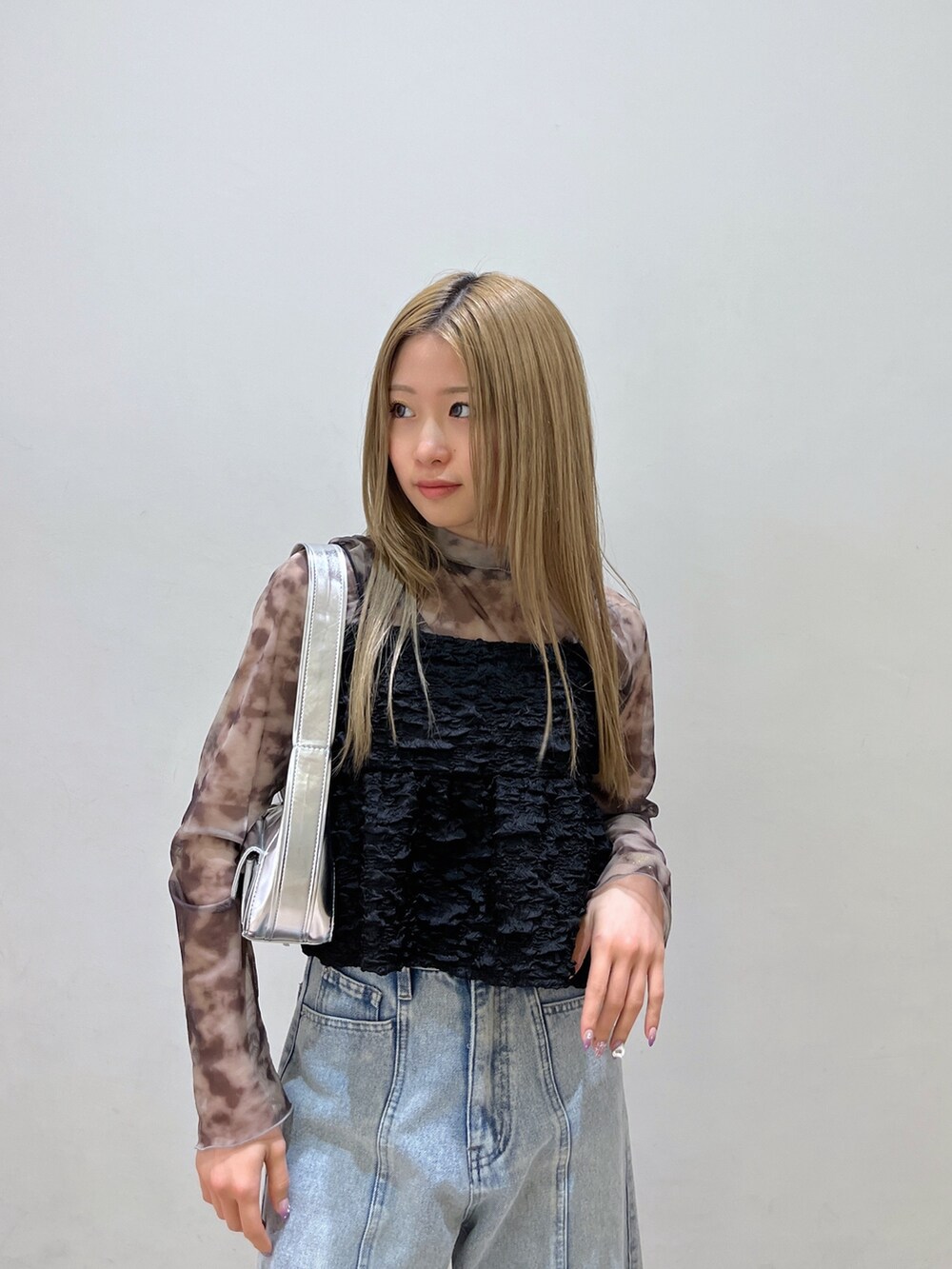 ブラック系のシャツ/ブラウス、シルバー系のショルダーバッグ、ブルー系のデニムパンツを着用したレディースの春コーディネートの6枚目の写真