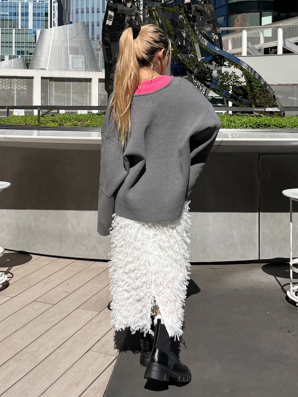 ブラック系のブーツ、ホワイト系のスカート、ピンク系のニット/セーターを着用したレディースの秋コーディネートの3枚目の写真