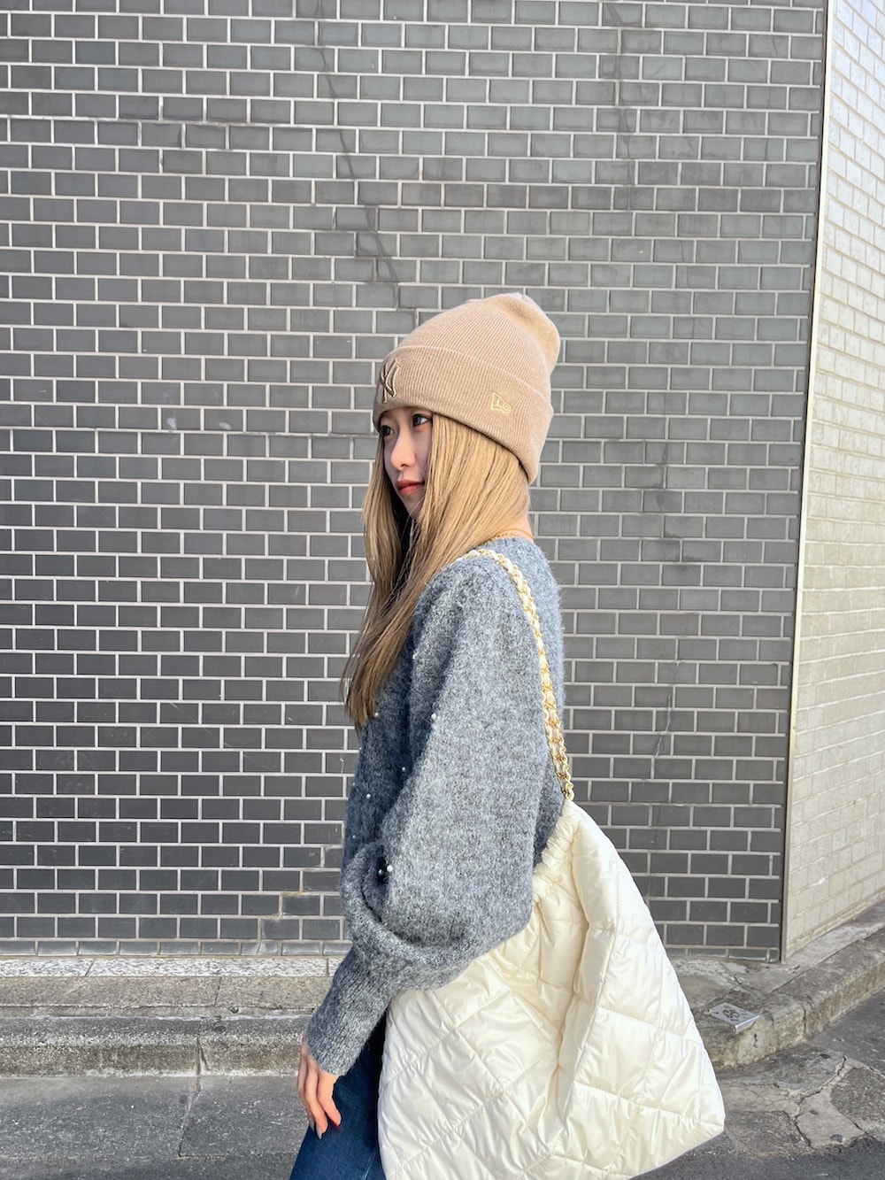 ブルー系のデニムパンツ、グレー系のニット/セーター、ホワイト系のトートバッグを着用したレディースの冬コーディネートの6枚目の写真