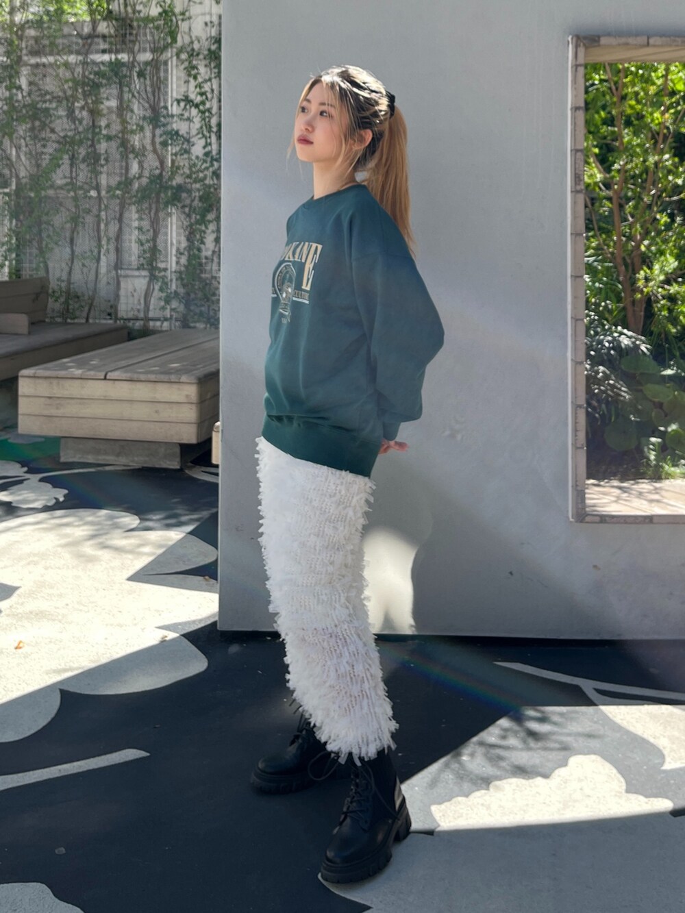 グリーン系のTシャツ/カットソー、ホワイト系のスカート、ブラック系のブーツを着用したレディースの秋コーディネートの3枚目の写真