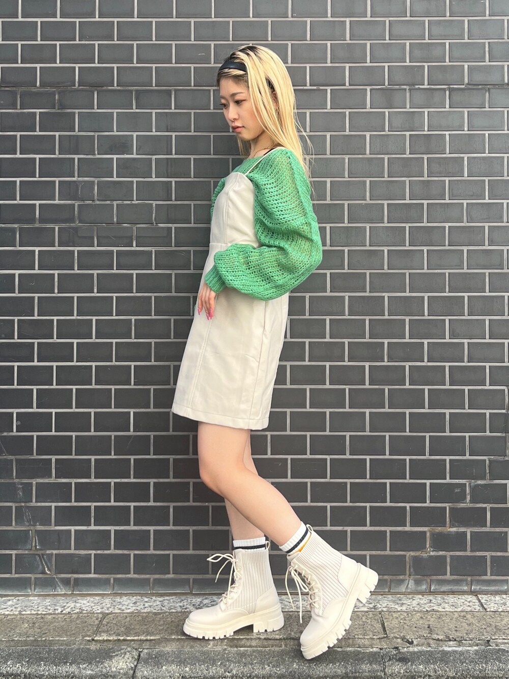 グリーン系のニット/セーター、ホワイト系のワンピース、ホワイト系のブーツを着用したレディースの秋コーディネートの2枚目の写真