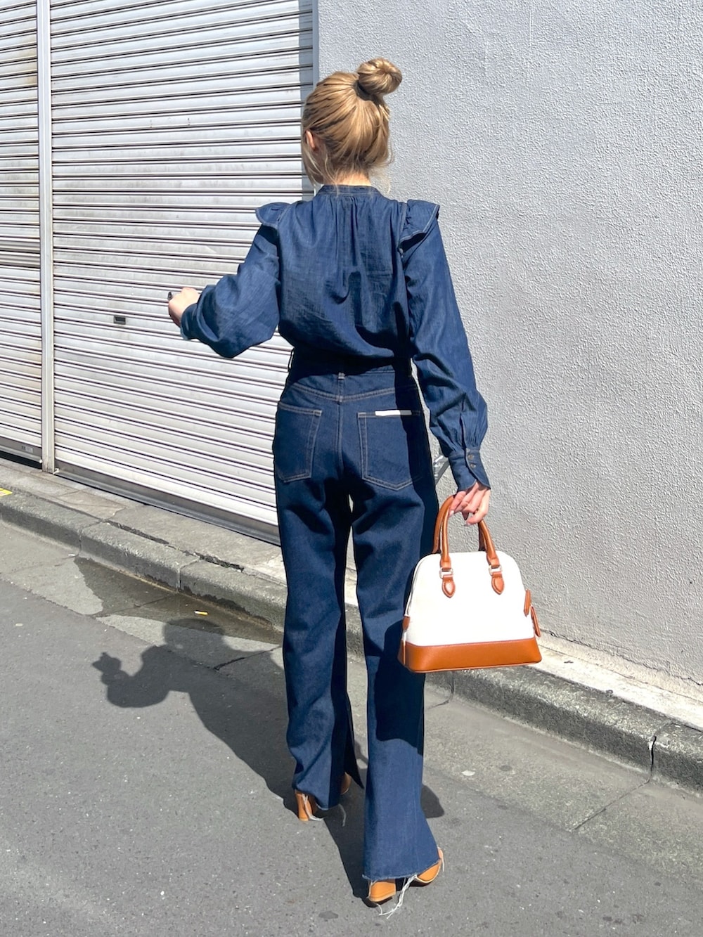 ブルー系のシャツ/ブラウス、ブルー系のデニムパンツ、ブラウン系のショルダーバッグを着用したレディースの春コーディネートの2枚目の写真