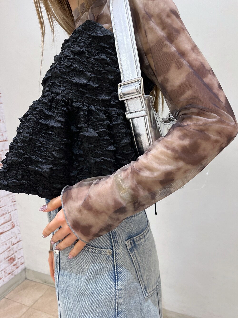 ブラック系のシャツ/ブラウス、シルバー系のショルダーバッグ、ブルー系のデニムパンツを着用したレディースの春コーディネートの9枚目の写真