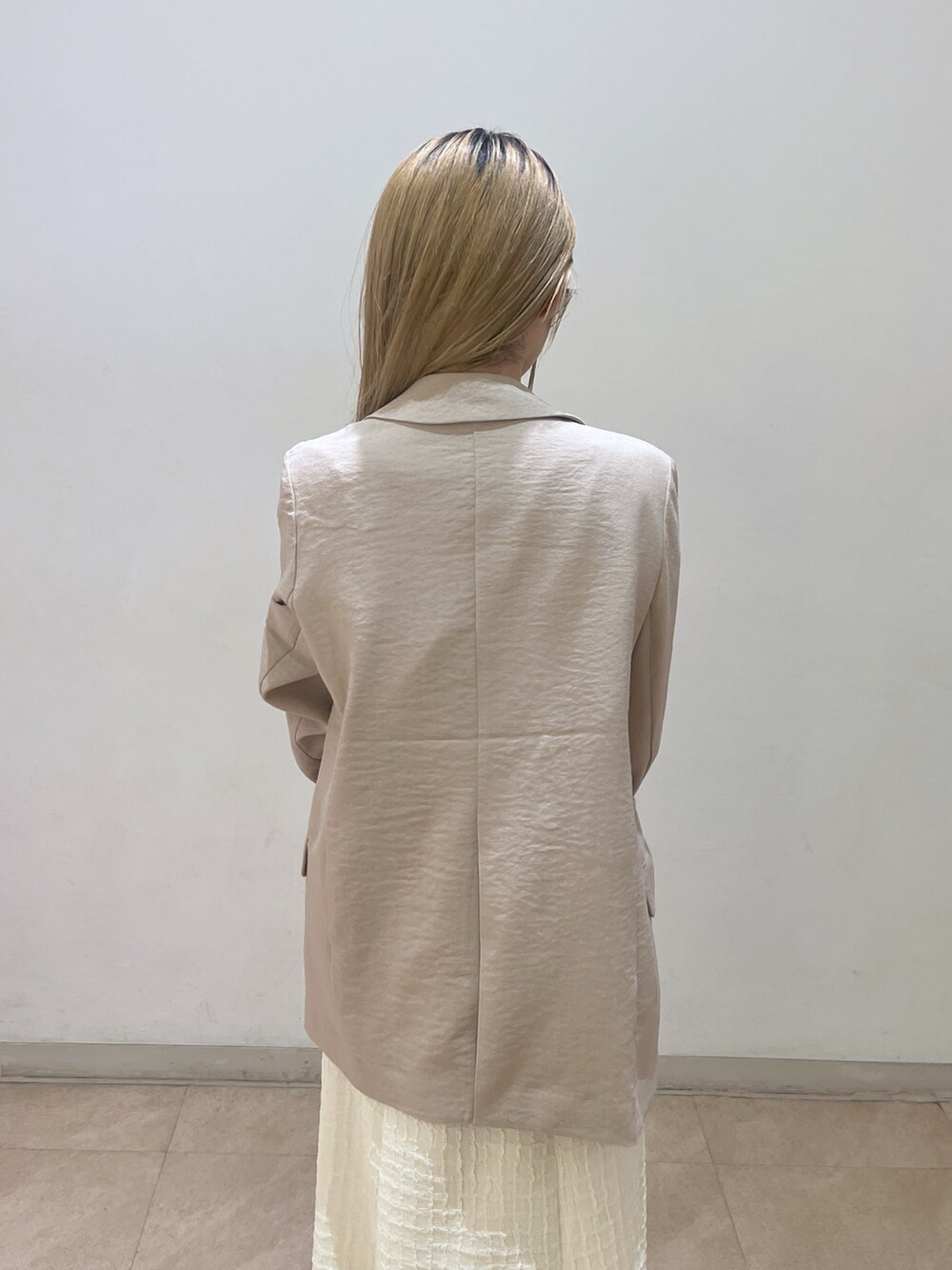 ベージュ系のテーラードジャケット、ブラウン系のショルダーバッグ、ホワイト系のワンピースを着用したレディースの春コーディネートの6枚目の写真