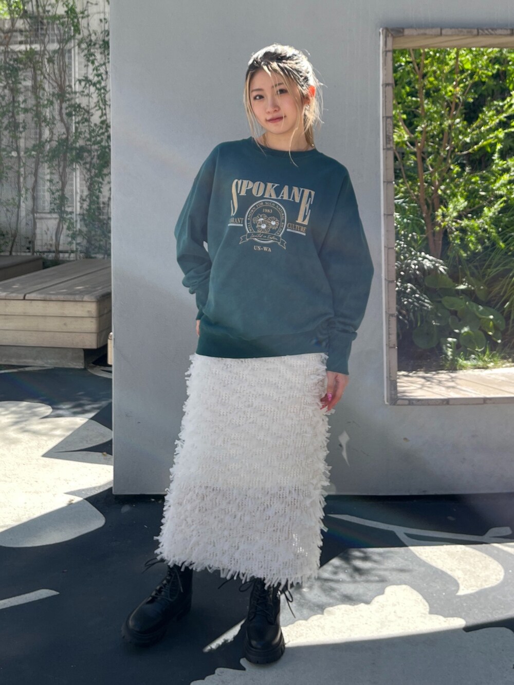 グリーン系のTシャツ/カットソー、ホワイト系のスカート、ブラック系のブーツを着用したレディースの秋コーディネートの2枚目の写真