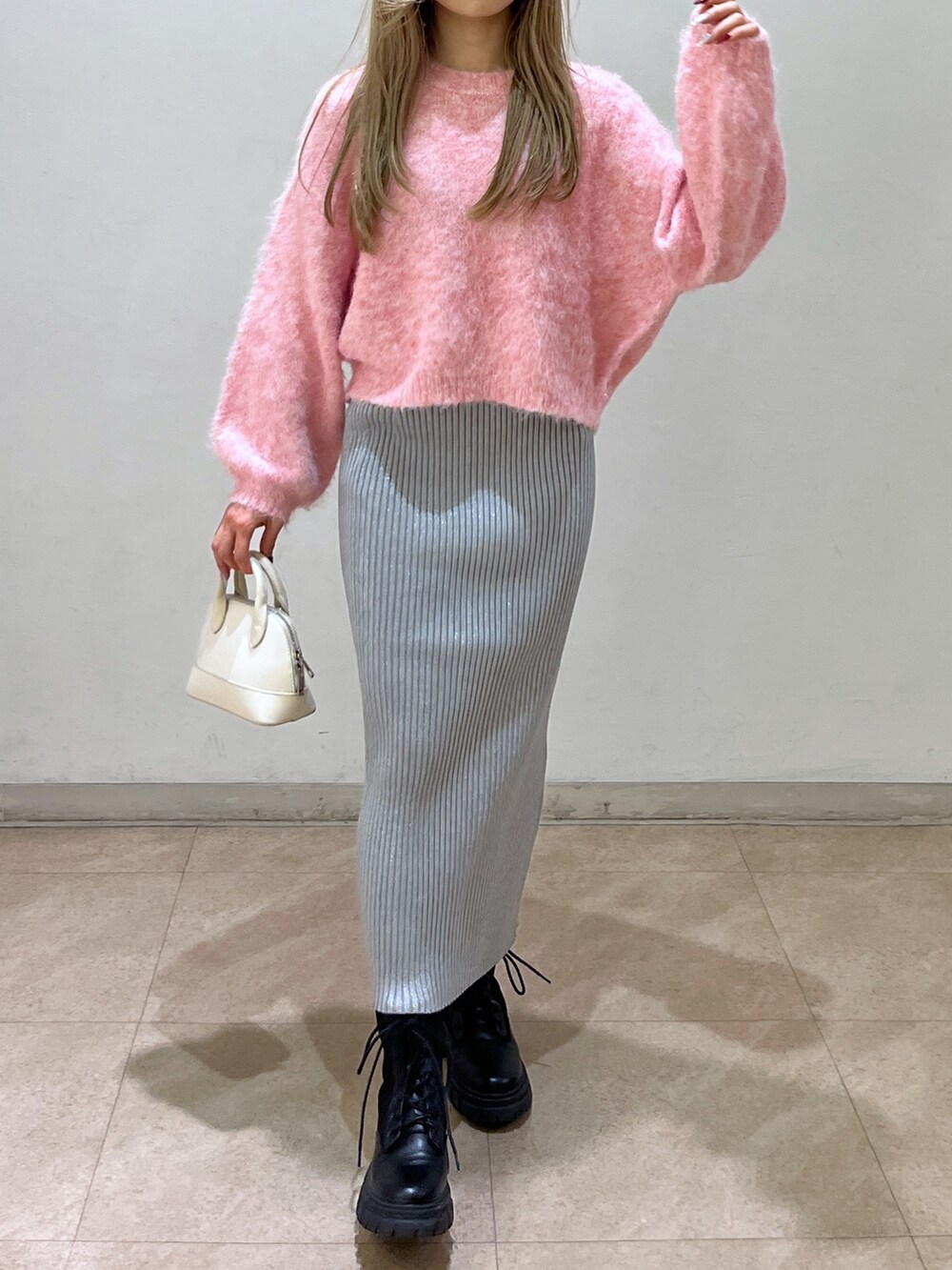 ピンク系のニット/セーター、ブラック系のブーツ、ホワイト系のショルダーバッグを着用したレディースの冬コーディネートの4枚目の写真