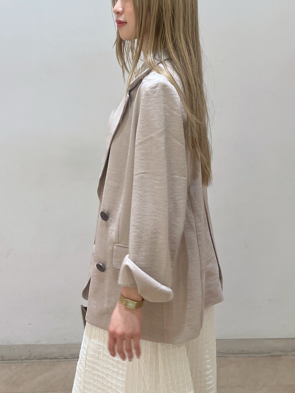 ベージュ系のテーラードジャケット、ブラウン系のショルダーバッグ、ホワイト系のワンピースを着用したレディースの春コーディネートの5枚目の写真