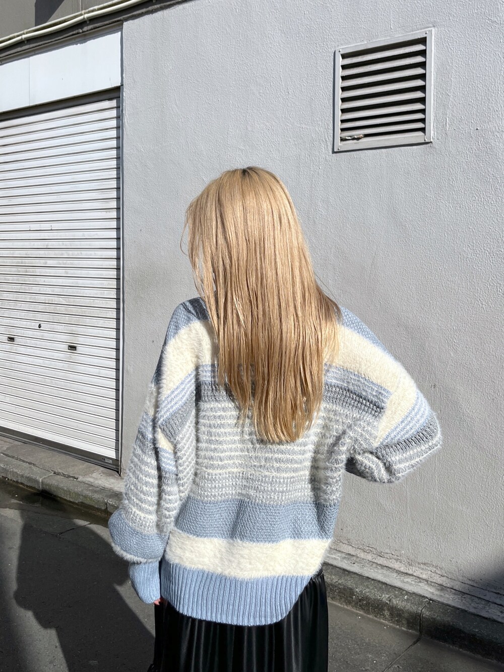 ブルー系のニット/セーター、ブラック系のスカート、ブラック系のブーツを着用したレディースの冬コーディネートの7枚目の写真