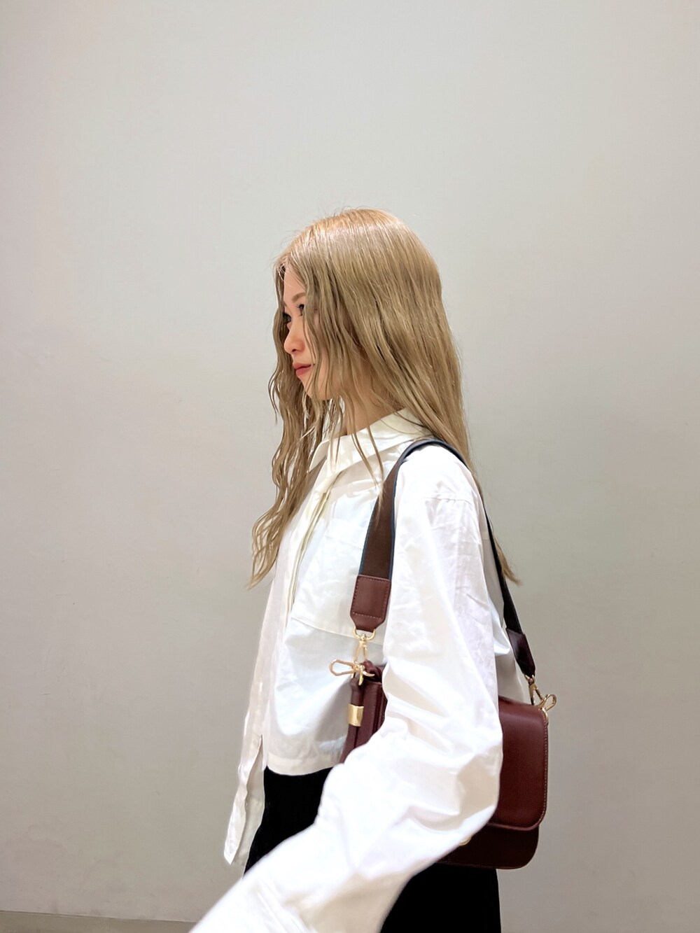 ブラック系のスカート、ホワイト系のシャツ/ブラウス、ブラウン系のショルダーバッグを着用したレディースの春コーディネートの6枚目の写真