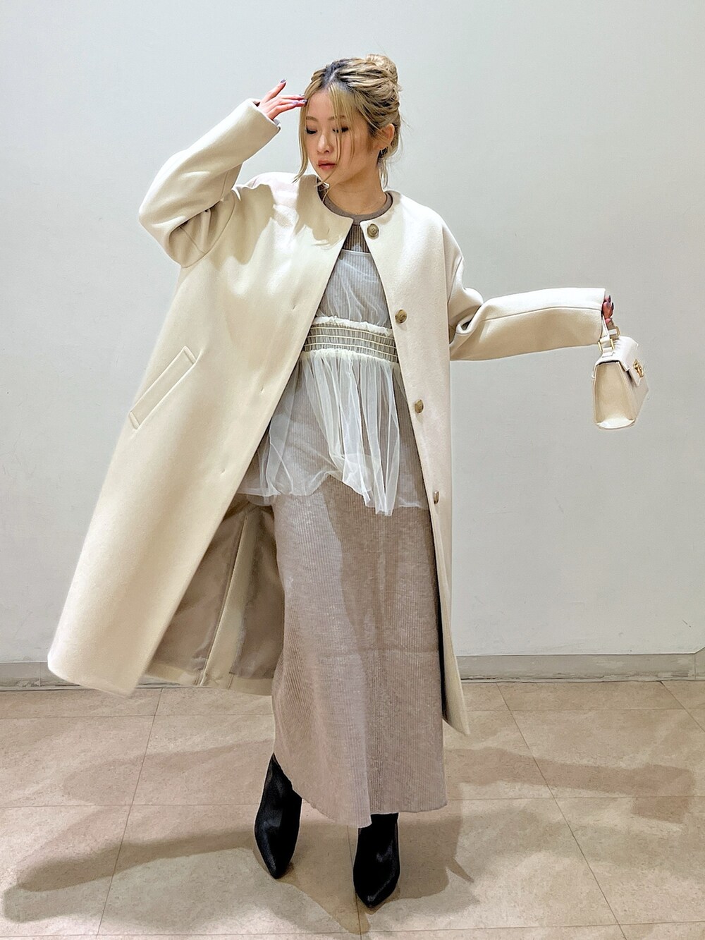ベージュ系のノーカラーコート、ホワイト系のシャツ/ブラウス、ベージュ系のワンピースを着用したレディースの冬コーディネートの4枚目の写真