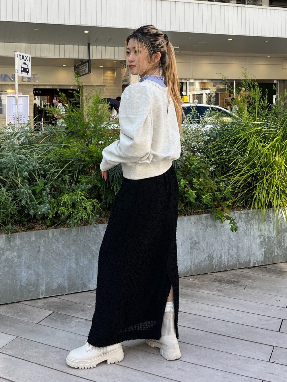 ホワイト系のスウェット、ホワイト系のブーツ、ブラック系のスカートを着用したレディースの秋コーディネートの4枚目の写真