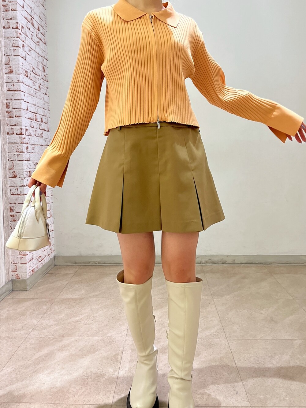 ベージュ系のニット/セーター、ホワイト系のショルダーバッグ、ベージュ系のスカートを着用したレディースの冬コーディネートの10枚目の写真