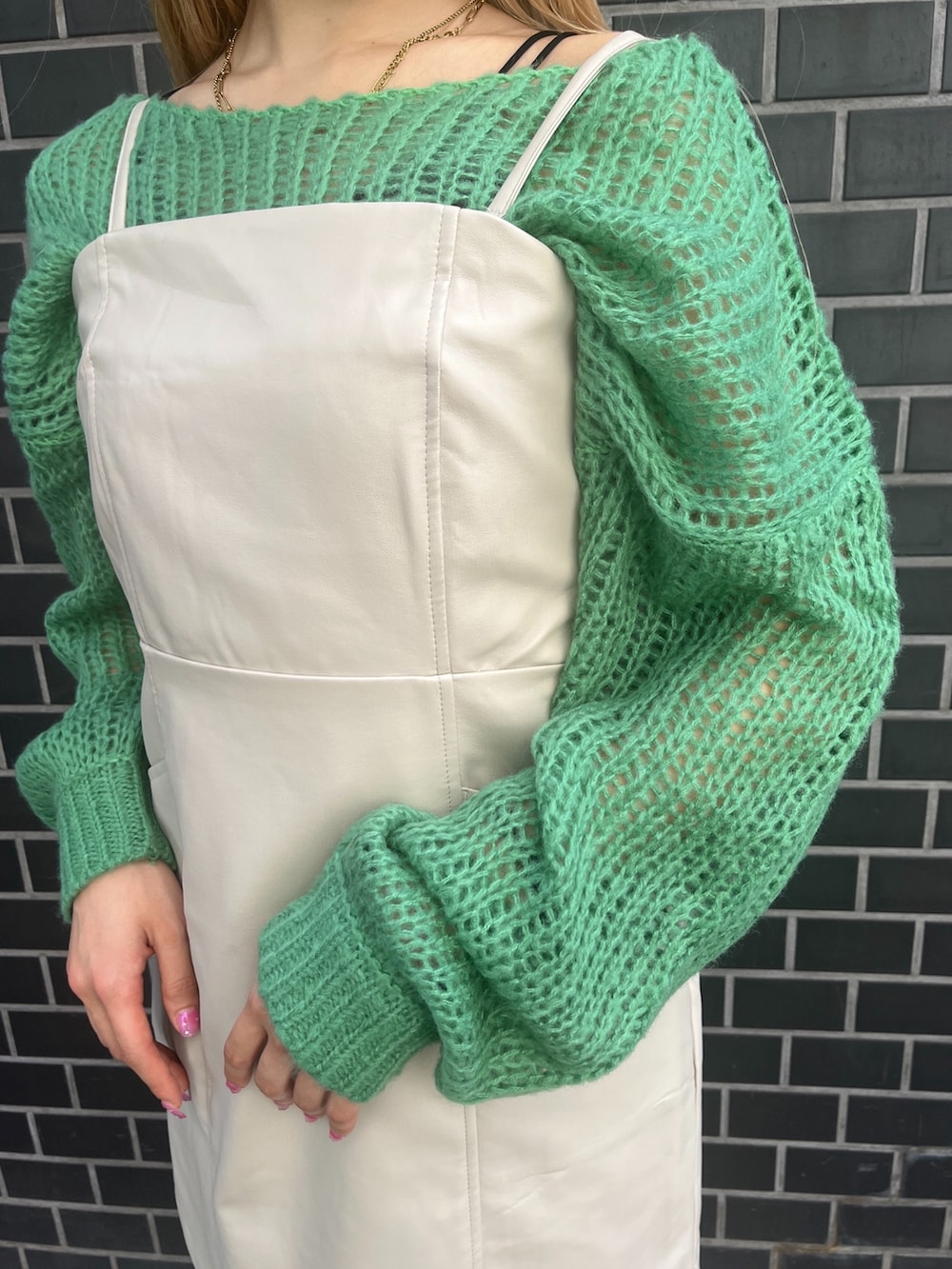 グリーン系のニット/セーター、ホワイト系のワンピース、ホワイト系のブーツを着用したレディースの秋コーディネートの8枚目の写真