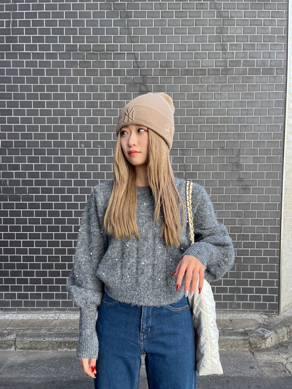 ブルー系のデニムパンツ、グレー系のニット/セーター、ホワイト系のトートバッグを着用したレディースの冬コーディネートの5枚目の写真