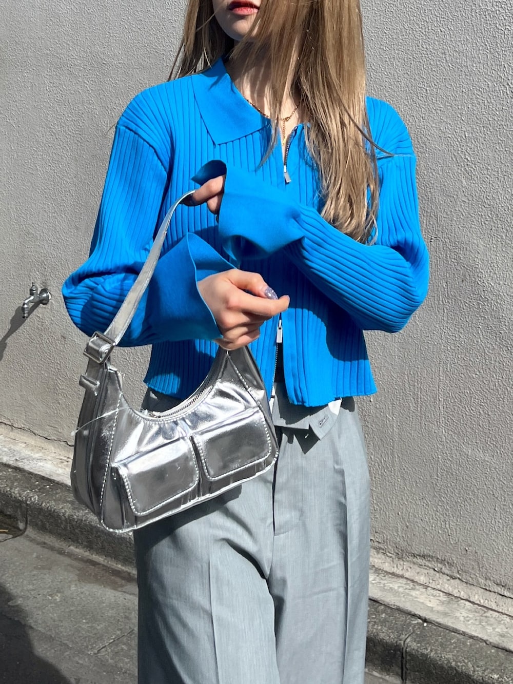 ブルー系のニット/セーター、シルバー系のショルダーバッグ、グレー系のスラックスを着用したレディースの春コーディネートの6枚目の写真