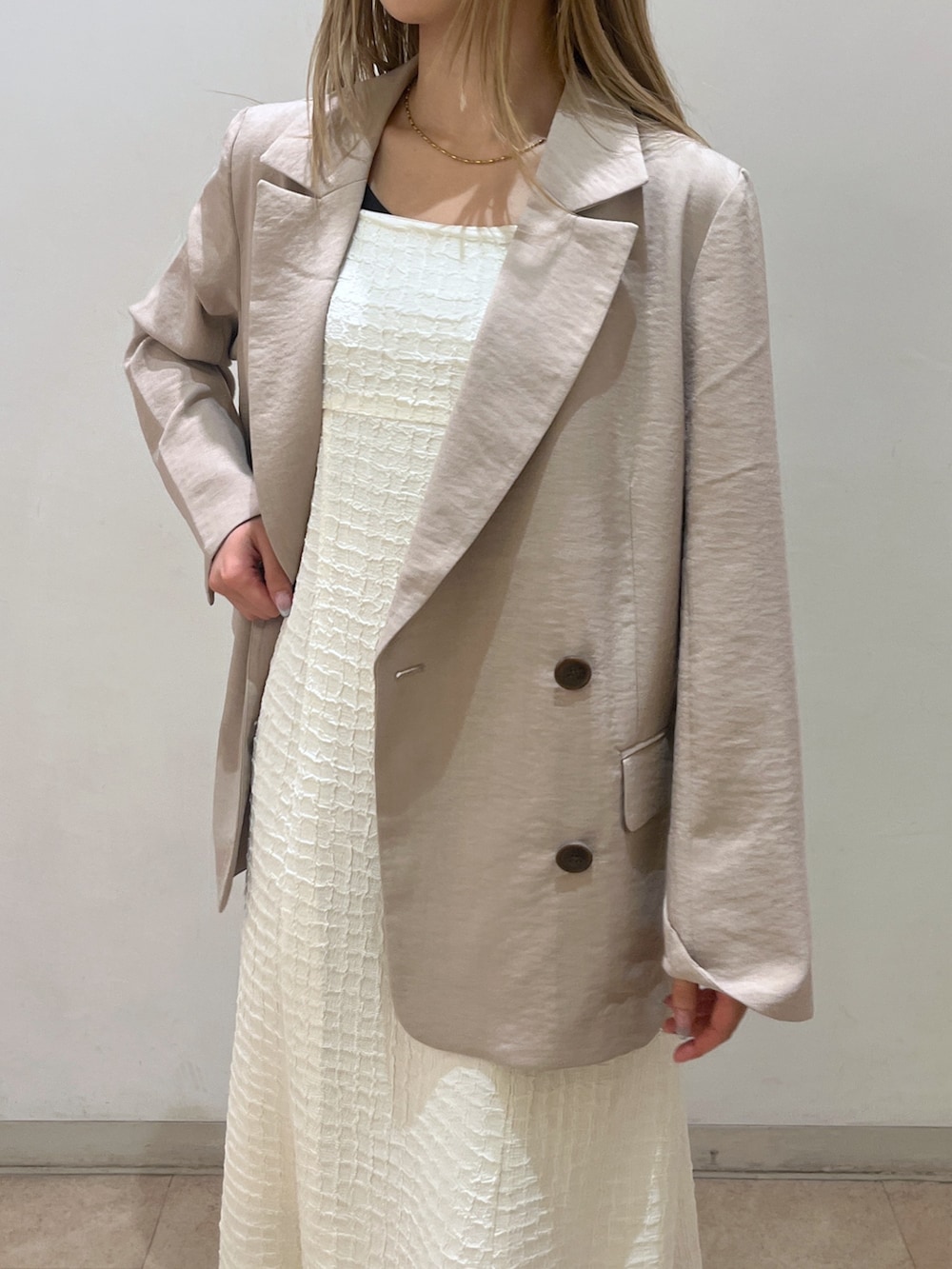 ベージュ系のテーラードジャケット、ブラウン系のショルダーバッグ、ホワイト系のワンピースを着用したレディースの春コーディネートの4枚目の写真