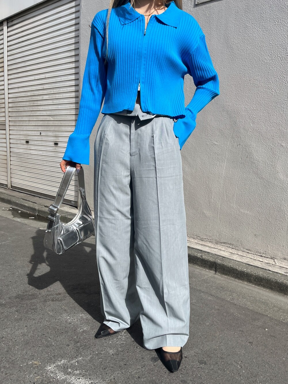 ブルー系のニット/セーター、シルバー系のショルダーバッグ、グレー系のスラックスを着用したレディースの春コーディネートの9枚目の写真