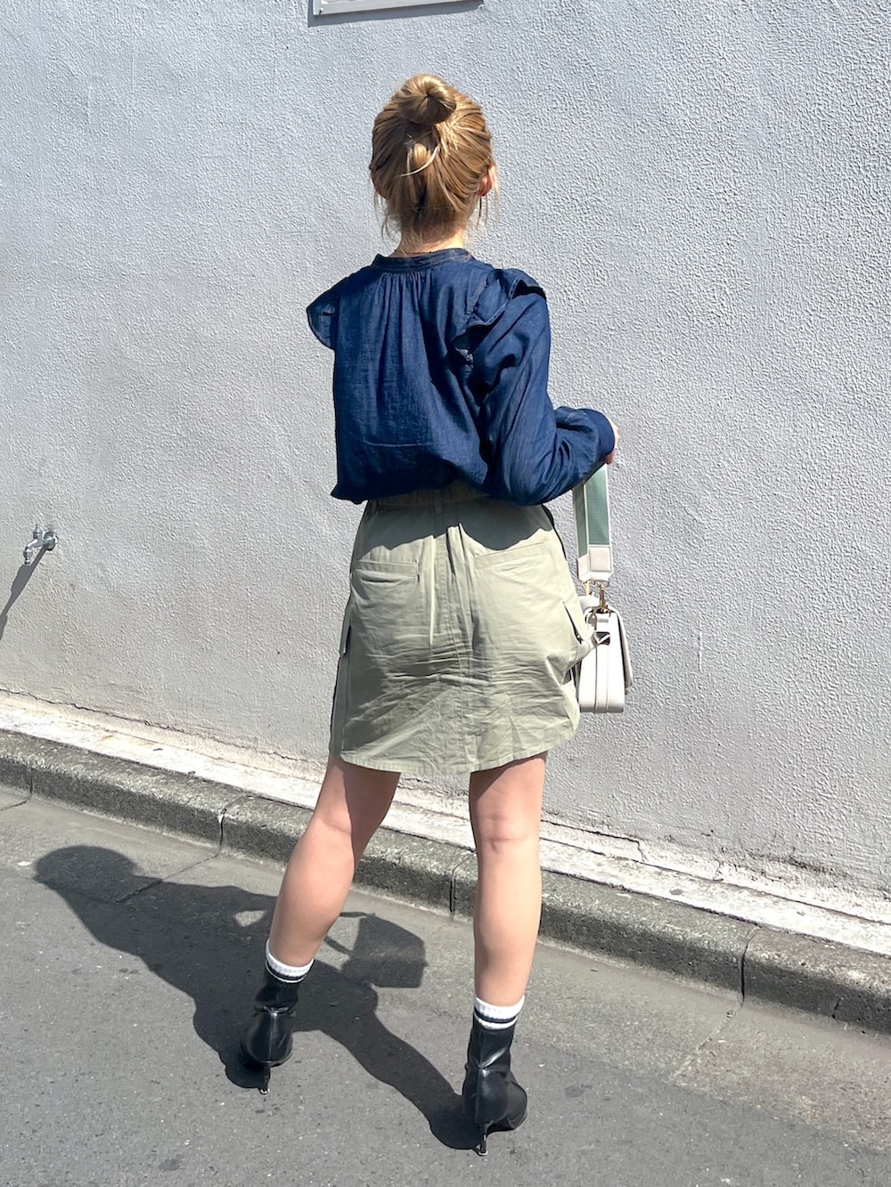 グリーン系のスカート、ホワイト系のショルダーバッグ、ブルー系のシャツ/ブラウスを着用したレディースの春コーディネートの4枚目の写真