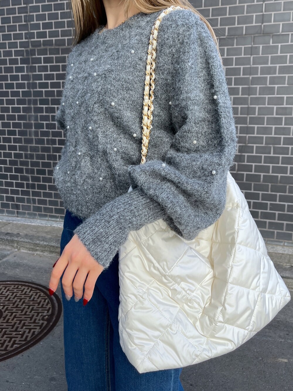 ブルー系のデニムパンツ、グレー系のニット/セーター、ホワイト系のトートバッグを着用したレディースの冬コーディネートの9枚目の写真