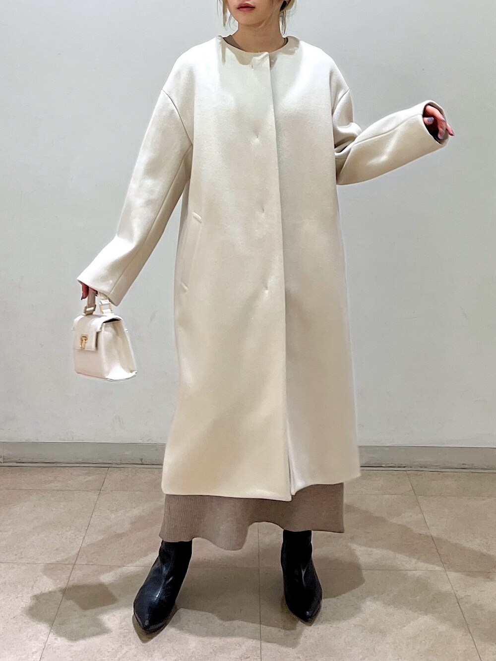 ベージュ系のノーカラーコート、ホワイト系のシャツ/ブラウス、ベージュ系のワンピースを着用したレディースの冬コーディネートの7枚目の写真