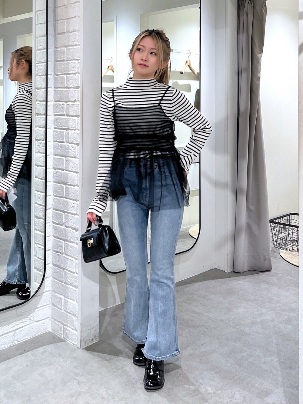 ホワイト系のニット/セーター、ブラック系のシャツ/ブラウス、ブルー系のデニムパンツを着用したレディースの冬コーディネートの3枚目の写真