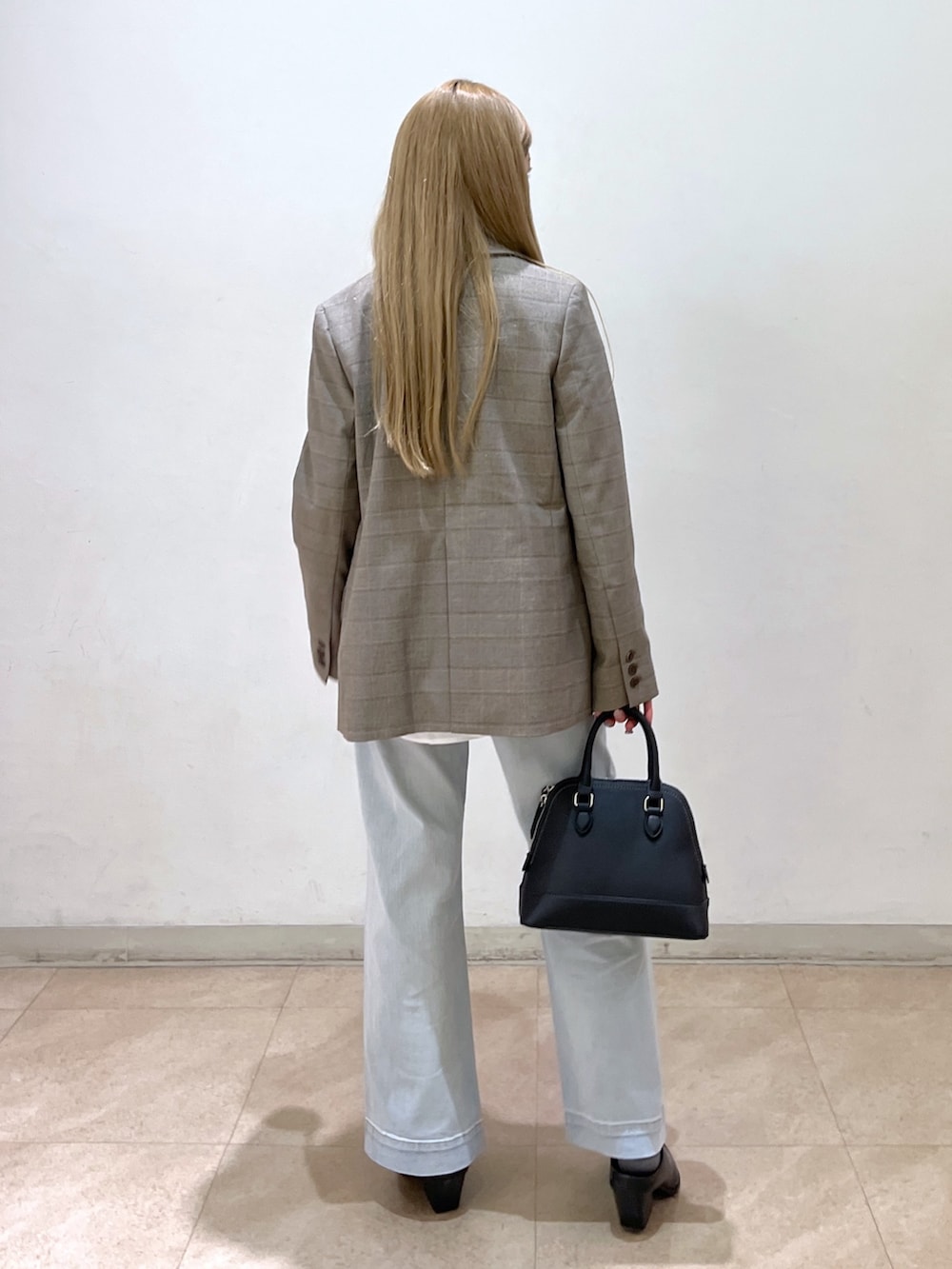 ブラック系のショルダーバッグ、ブルー系のデニムパンツ、ブラック系のパンプスを着用したレディースの春コーディネートの4枚目の写真