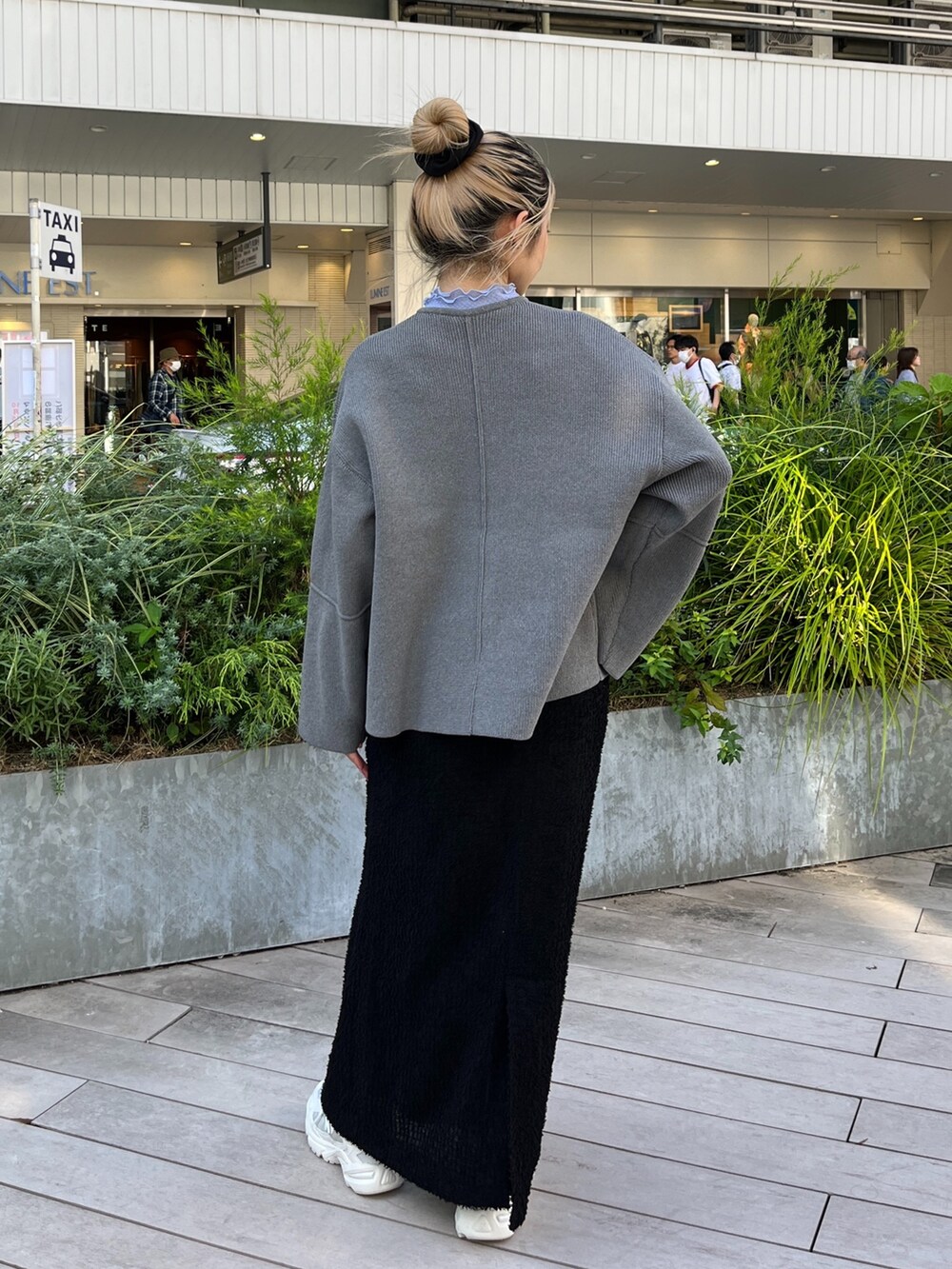 グレー系のカーディガン/ボレロ、ブラック系のスカート、ホワイト系のスニーカーを着用したレディースの秋コーディネートの4枚目の写真