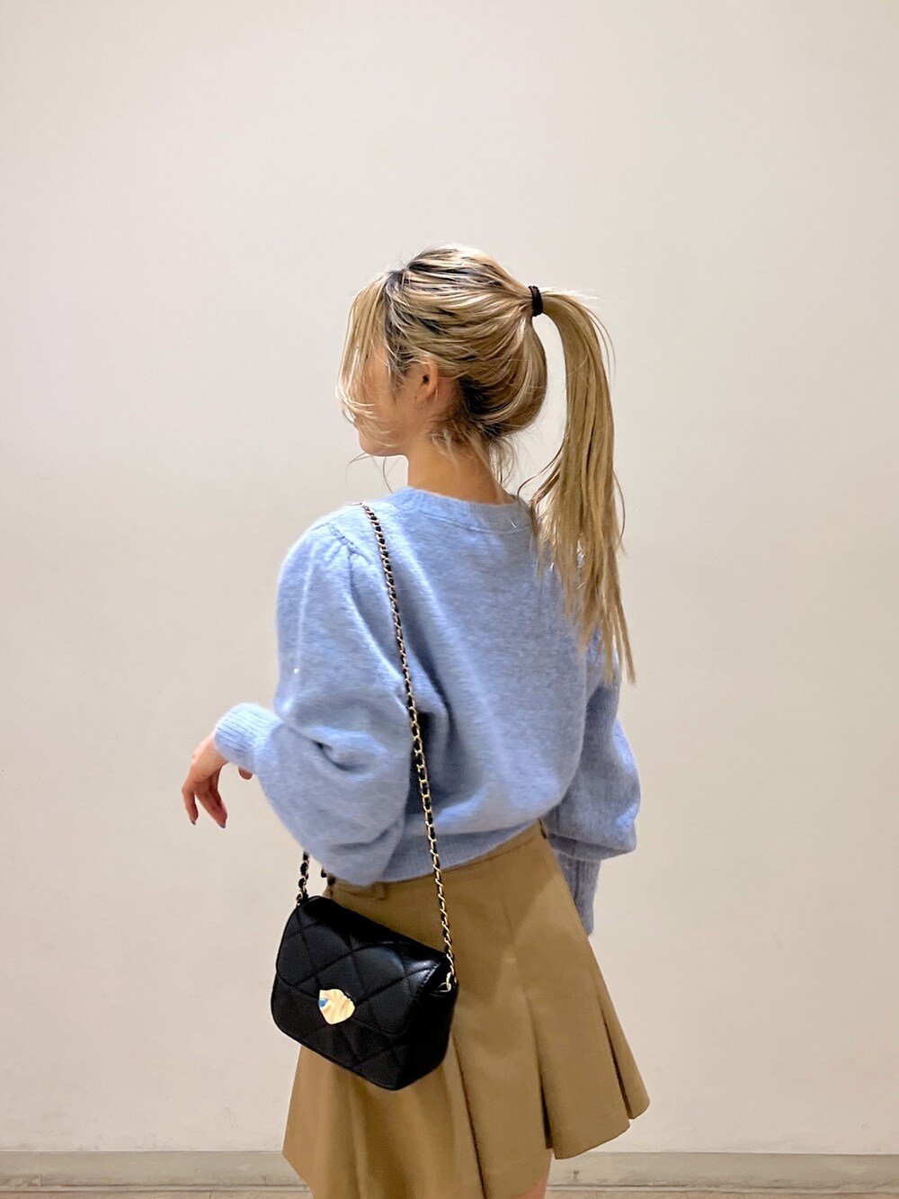 ブルー系のニット/セーター、ブラック系のショルダーバッグ、ベージュ系のスカートを着用したレディースの冬コーディネートの9枚目の写真