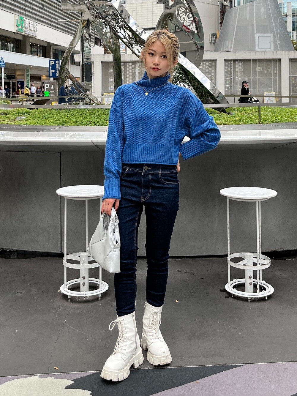 ブルー系のニット/セーター、ブルー系のデニムパンツ、シルバー系のショルダーバッグを着用したレディースの秋コーディネートの2枚目の写真