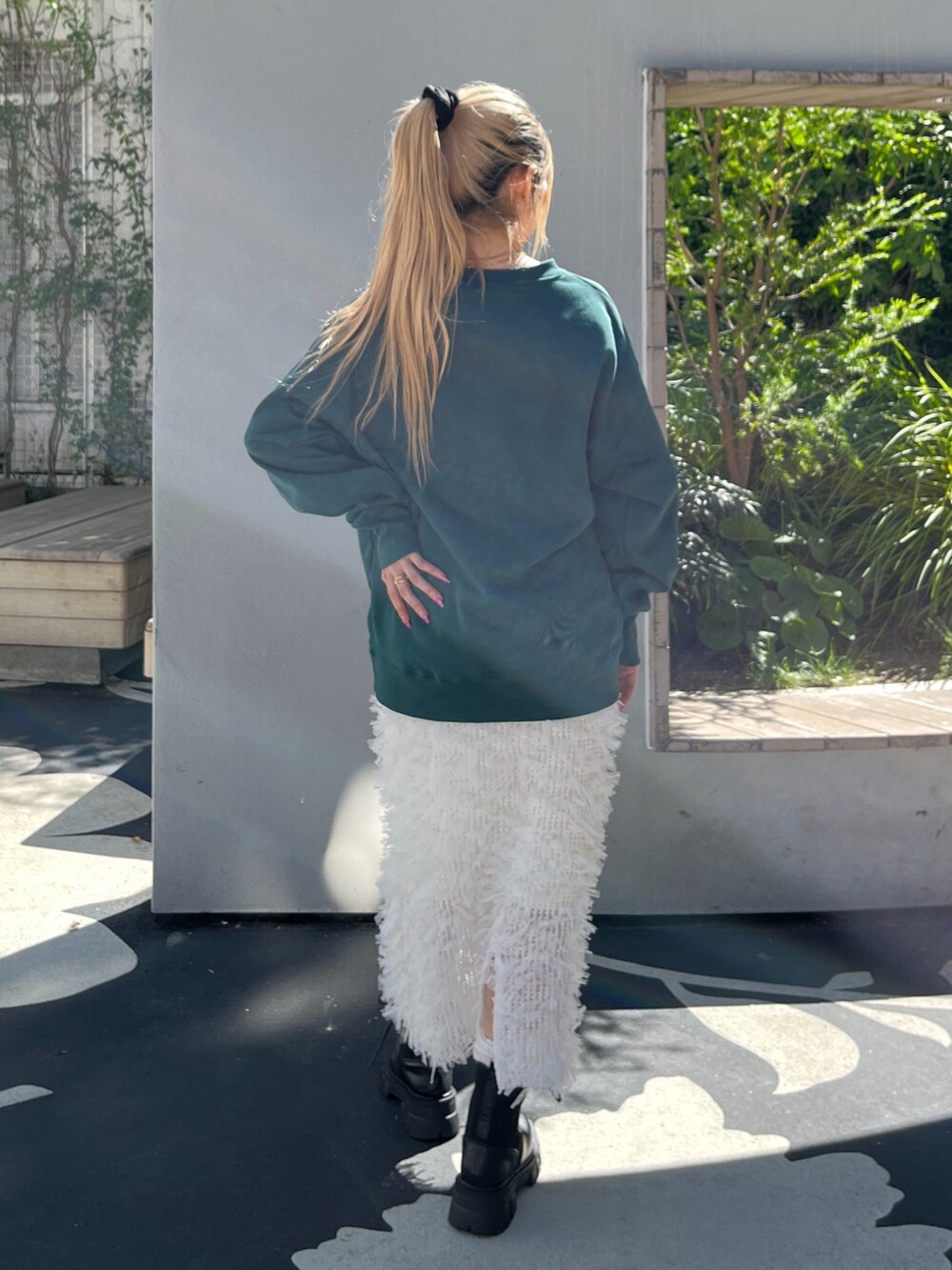 グリーン系のTシャツ/カットソー、ホワイト系のスカート、ブラック系のブーツを着用したレディースの秋コーディネートの4枚目の写真