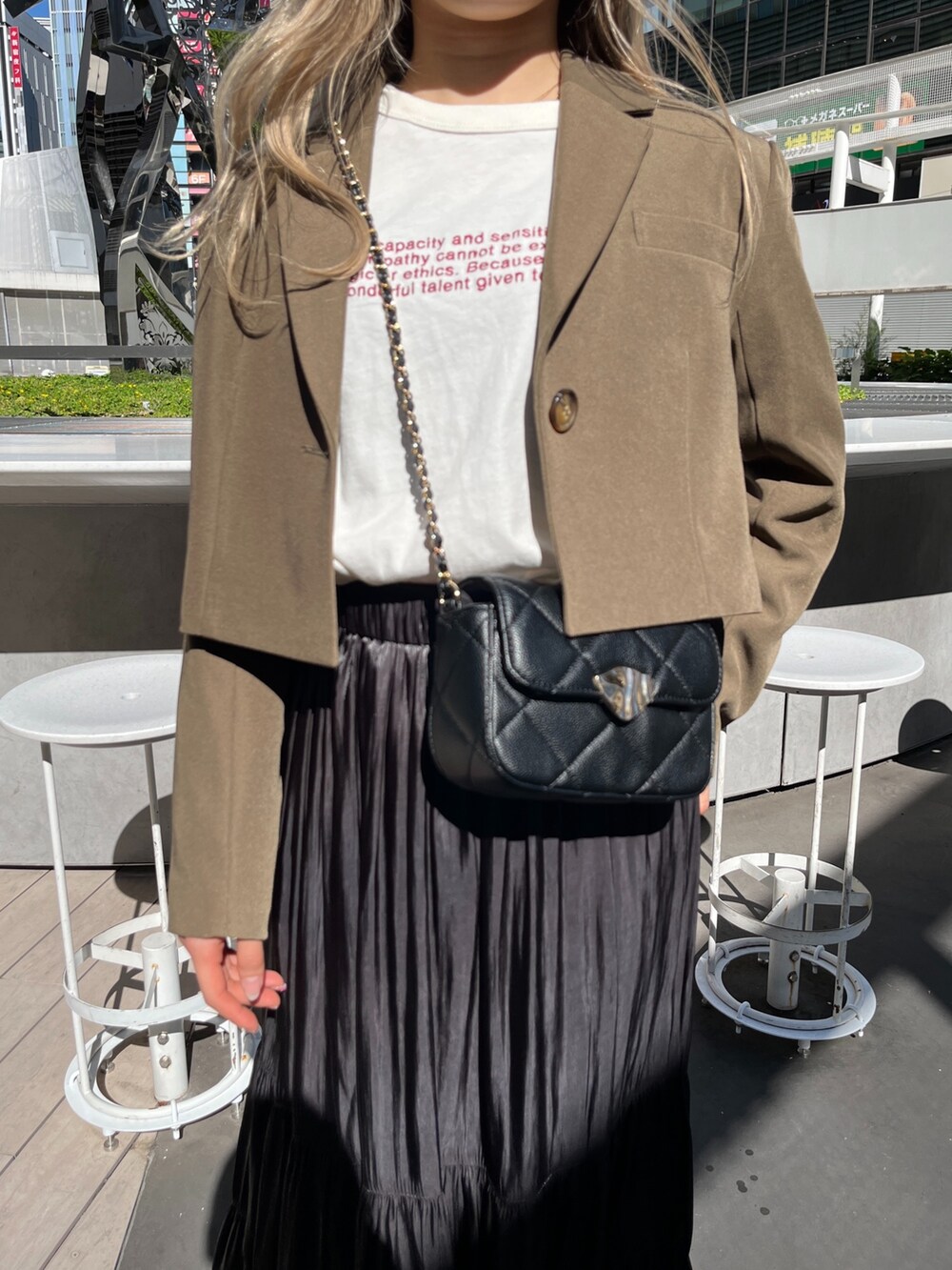 ブラック系のショルダーバッグ、ホワイト系のTシャツ/カットソー、ブラウン系のテーラードジャケットを着用したレディースの秋コーディネートの7枚目の写真