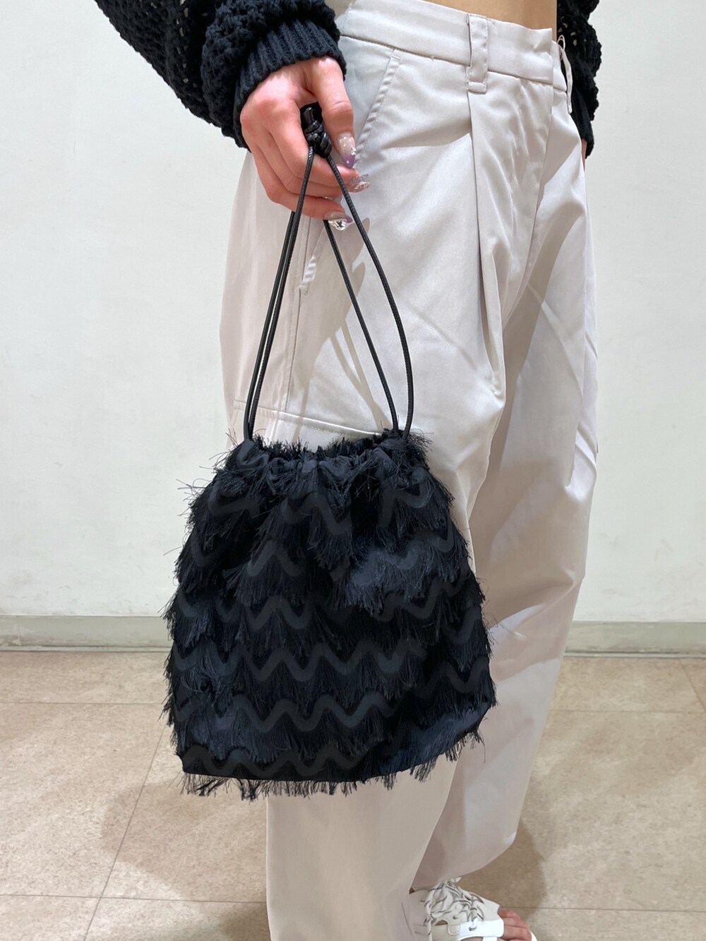 ベージュ系のカーゴパンツ、ブラック系のニット/セーター、ブラック系のハンドバッグを着用したレディースの春コーディネートの10枚目の写真