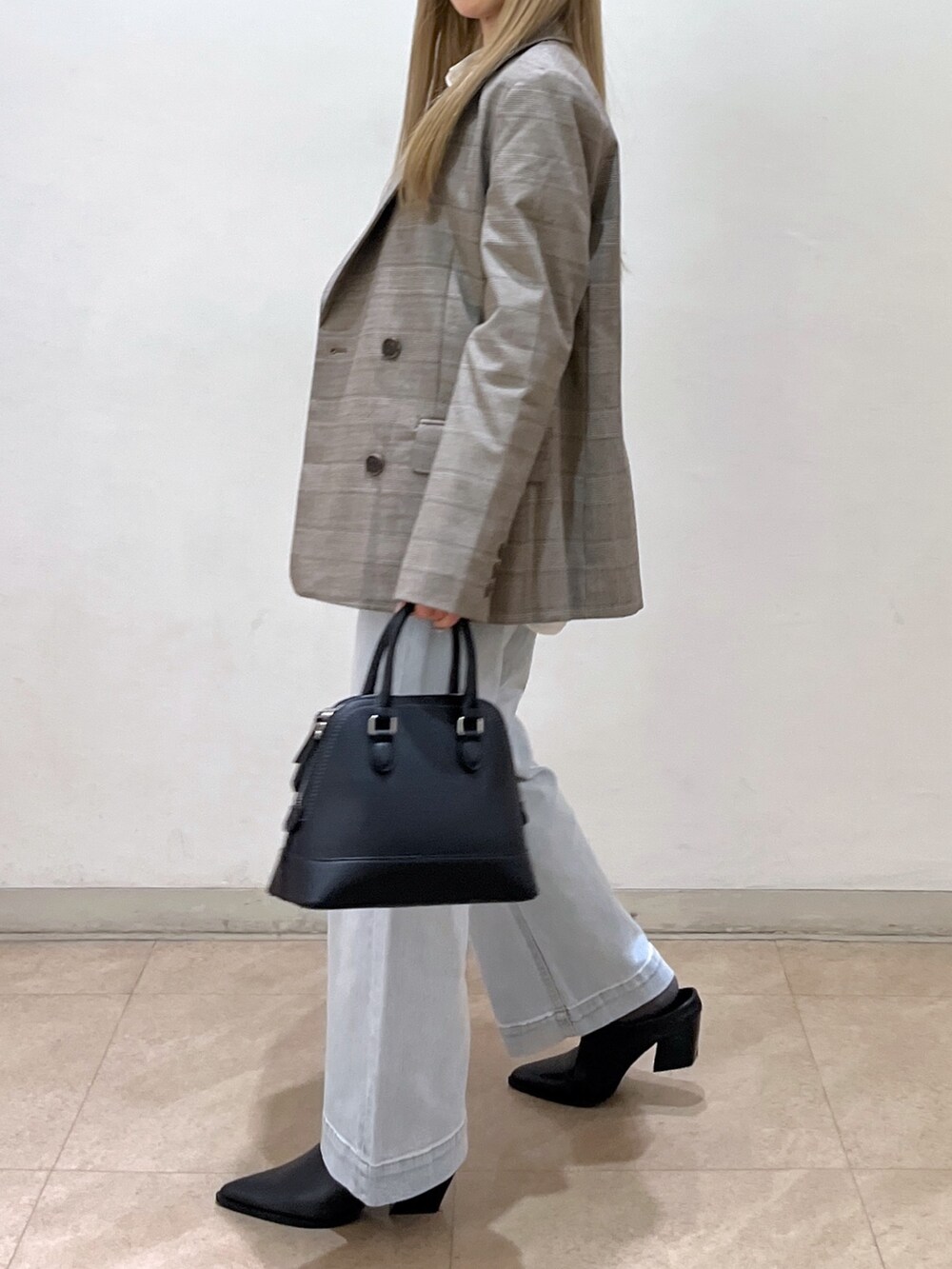 ブラック系のショルダーバッグ、ブルー系のデニムパンツ、ブラック系のパンプスを着用したレディースの春コーディネートの5枚目の写真