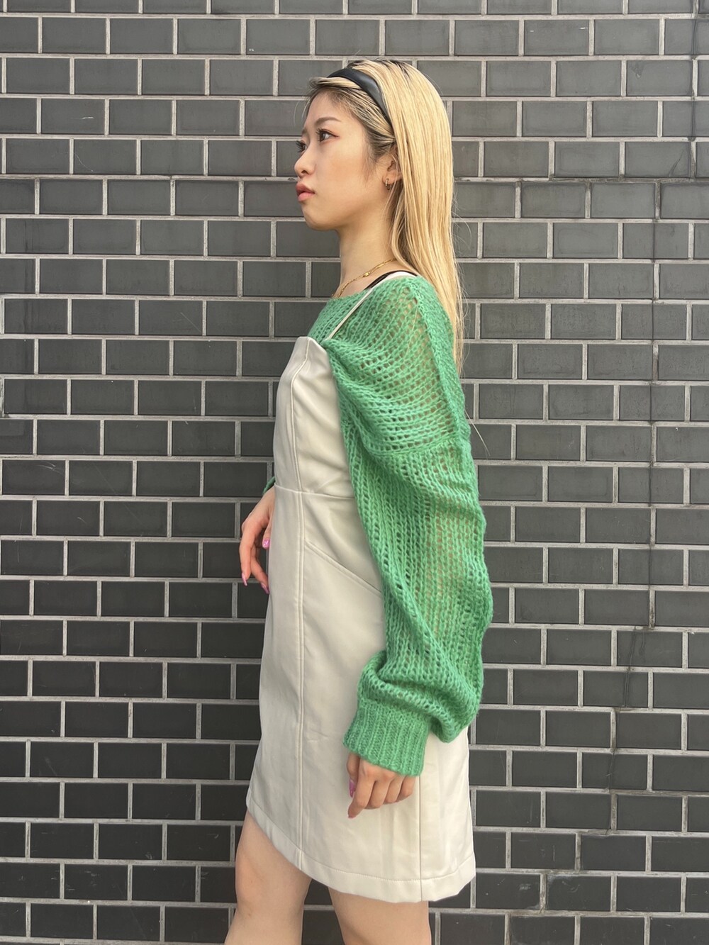 グリーン系のニット/セーター、ホワイト系のワンピース、ホワイト系のブーツを着用したレディースの秋コーディネートの6枚目の写真