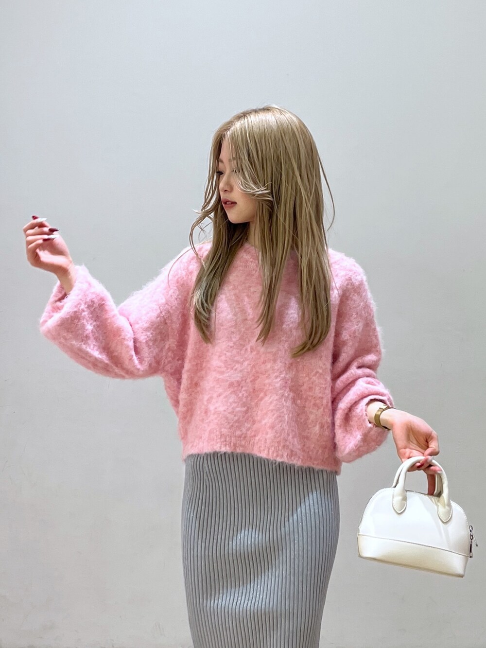 ピンク系のニット/セーター、ブラック系のブーツ、ホワイト系のショルダーバッグを着用したレディースの冬コーディネートの6枚目の写真